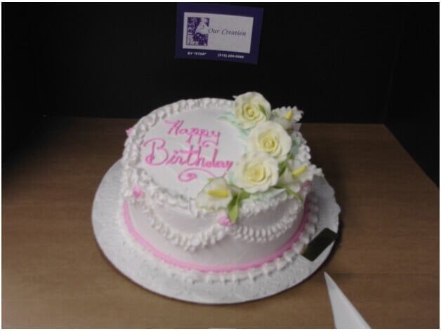 White birthday cake with pink script that reads 