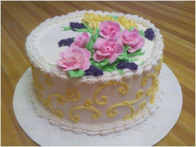 Cake decorated with pink and yellow frosting flowers and swirls.