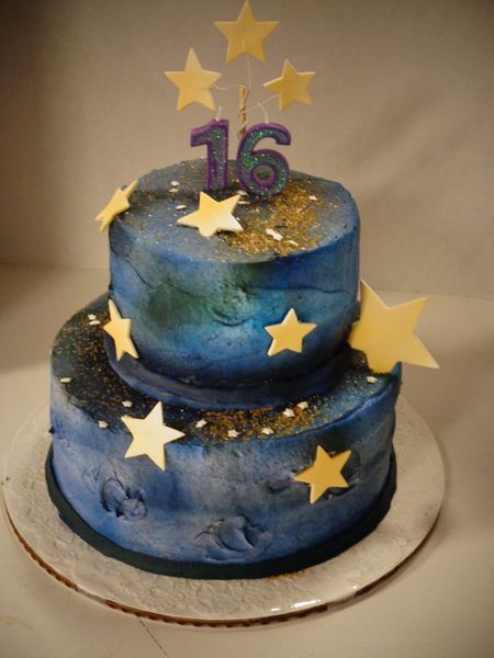 Two-tiered blue cake decorated with white stars and gold sprinkles; 