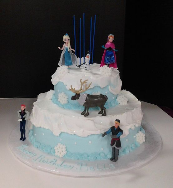 Two-tiered Frozen-themed birthday cake with Elsa, Anna, Olaf, and Sven figurines; blue frosting with white accents, candles.