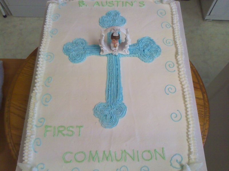 White rectangular cake with a blue cross, a figurine, and text reading 