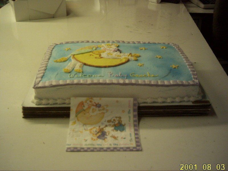 Baby shower cake with moon and stars, a light blue frosted rectangular cake with white frosting and a napkin with a matching design.