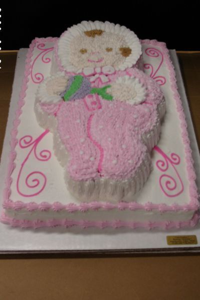 Cake decorated as a baby in pink with curly designs on a white rectangular base.