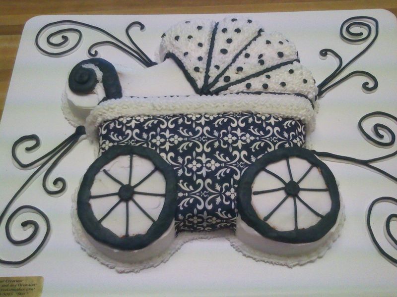Baby carriage cake, decorated in blue and white, with swirled icing details.