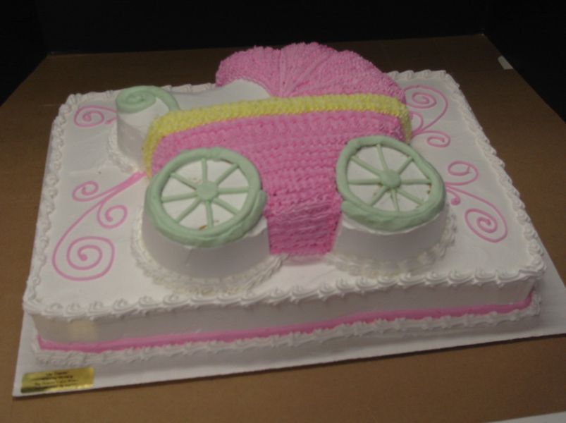 Pink baby carriage cake with yellow stripe, green wheels, and decorative swirls.
