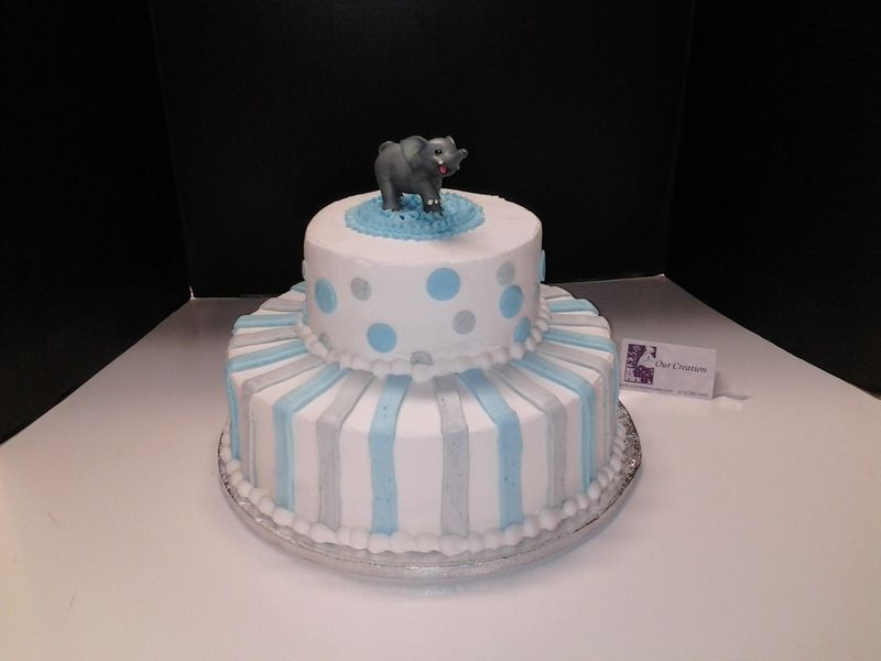 Two-tiered baby shower cake with blue, gray, and white stripes and polka dots. Elephant topper.