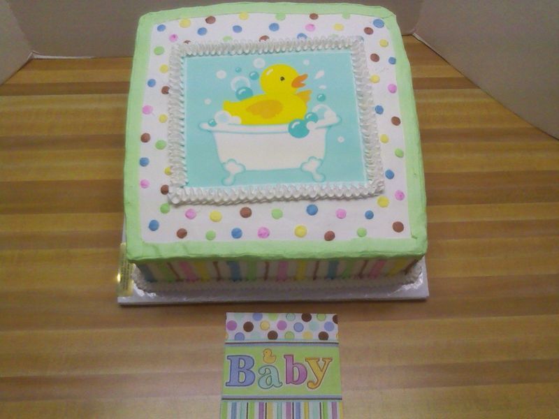 Baby shower cake with rubber duck in bathtub, topped with polka dots and a 