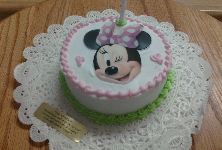 Minnie Mouse birthday cake with pink frosting, sitting on a doily.