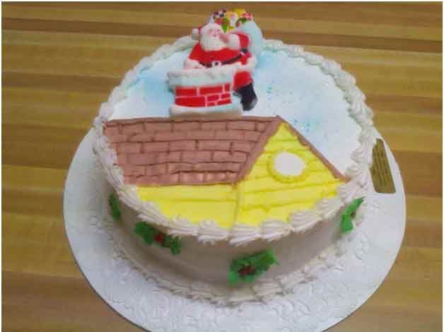 Christmas cake decorated with Santa on a rooftop, chimney, house, and holly.