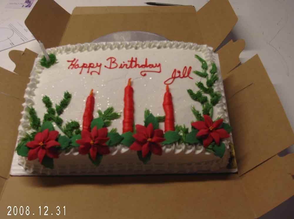 Birthday cake in a box with red candles and flowers, white frosting, and 
