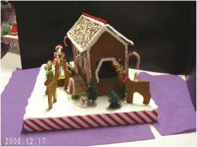 Gingerbread house with candy cane accents and miniature figures on a snowy base, festive setting.