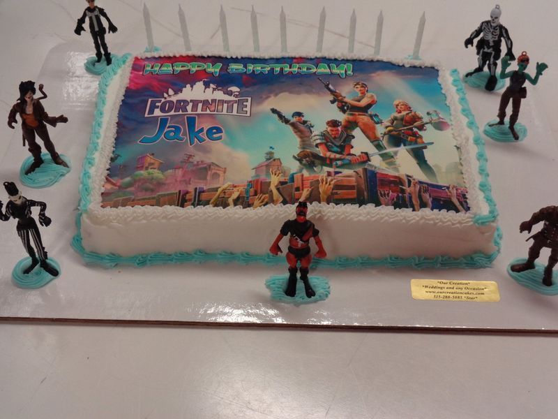 Fortnite birthday cake with a colorful image and character figurines, candles, and 