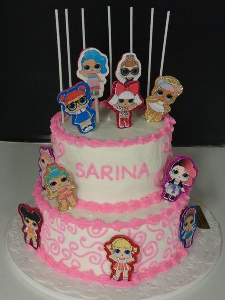 Two-tiered birthday cake decorated with pink frosting, LOL Surprise dolls, and 