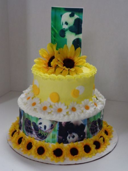 Three-tiered cake with panda print and sunflowers, yellow frosting, and a panda image on top.