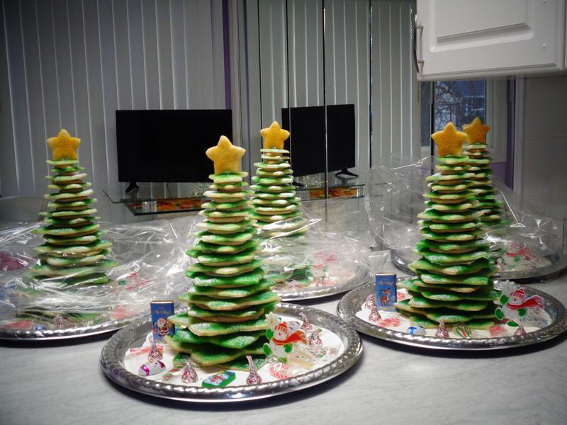Cookie Christmas trees on silver platters, topped with gold stars, set on a kitchen counter.