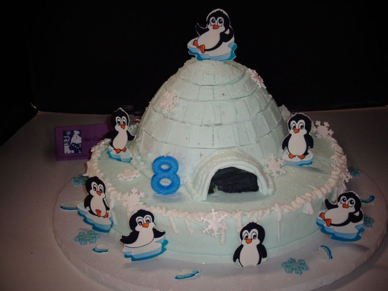 Birthday cake with an igloo, penguins, and the number 8.