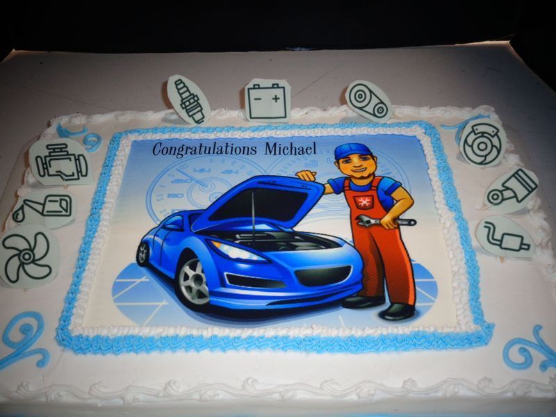 Cake decorated for Michael, featuring a blue car, mechanic, and auto parts. 