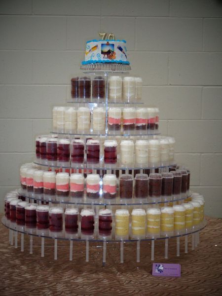 Cake tower with small cakes on multiple tiers, topped with a small cake with the number 70.