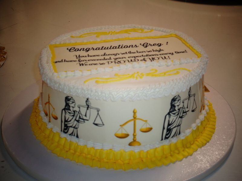 Cake decorated for a lawyer. White frosting with yellow accents, scales of justice, and congratulations message.