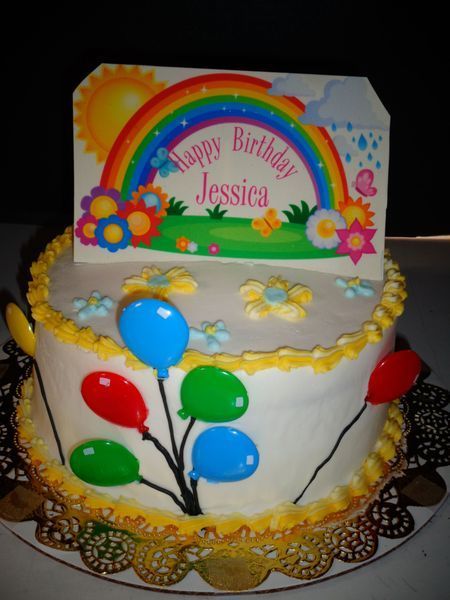 Birthday cake with balloons and a rainbow card topper that says 
