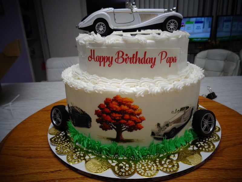 Two-tier birthday cake with a model car on top. 