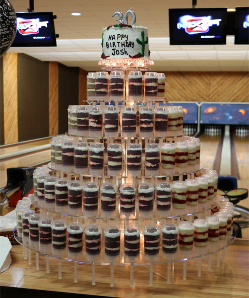 Birthday cake made of stacked shot glasses with a small cake on top in a bowling alley.