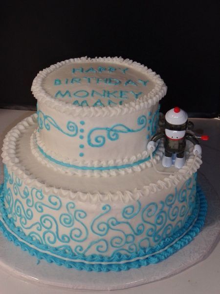 Two-tiered white cake with blue scrollwork and trim. 