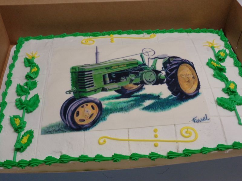 Cake decorated with a green tractor design, on a white background with green and yellow accents.