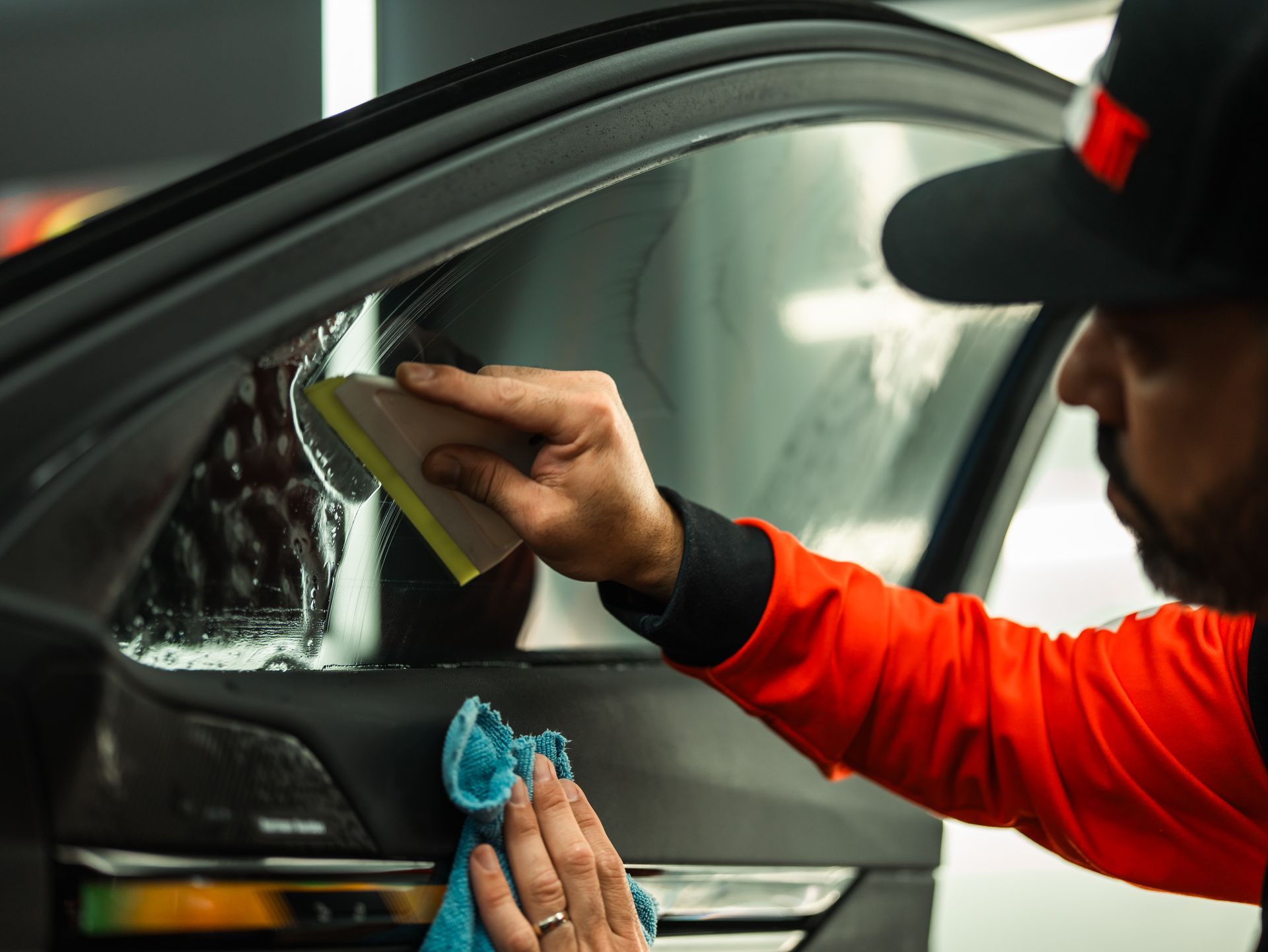 A man is applying tinted glass to a car window.