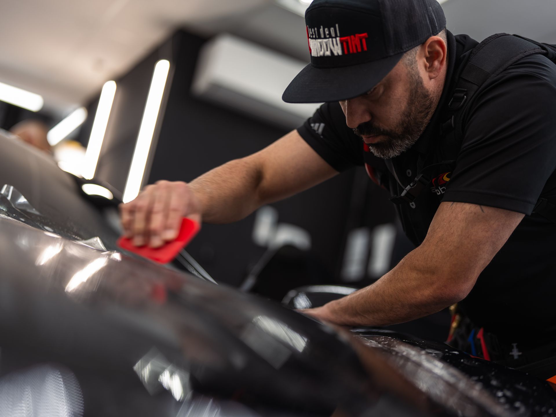 A man wearing a hat is working on a car.