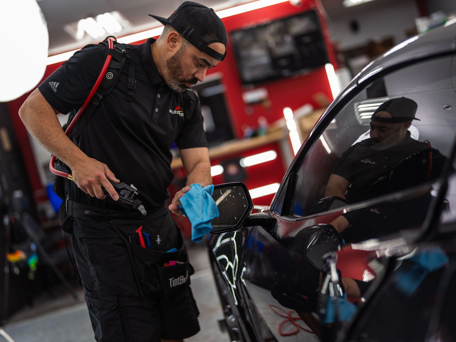 A man is cleaning a car with a towel in a garage.