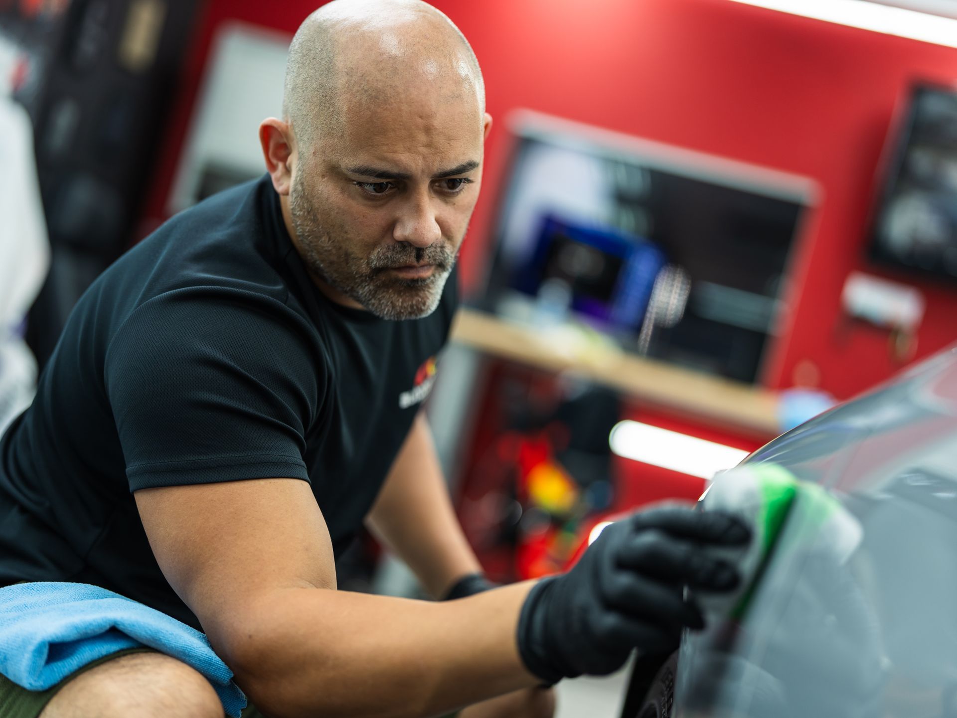 A man is cleaning a car with a sponge in a garage.