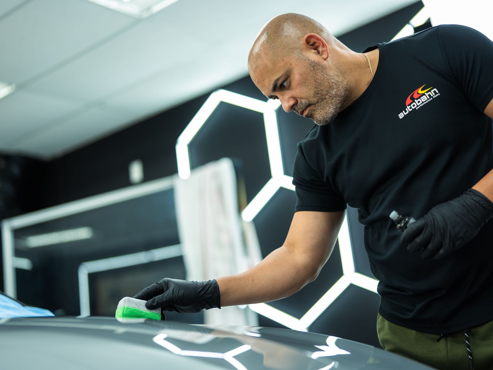 A man in a black shirt is polishing a car
