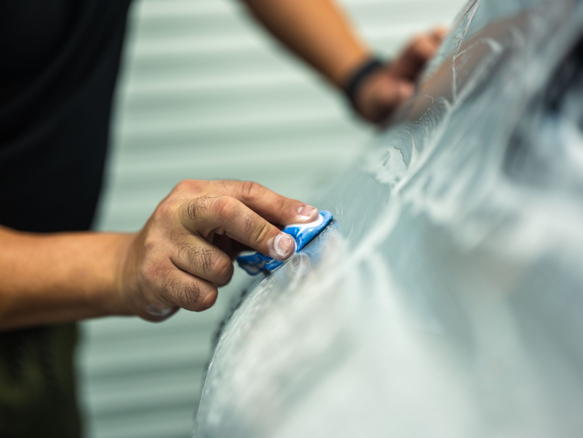 A man is wrapping a car with plastic wrap.