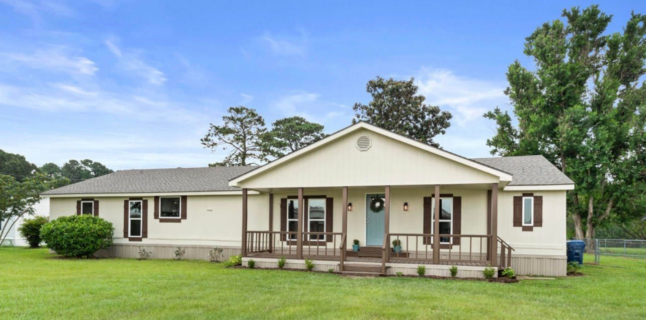 a white house with a porch and trees in the background