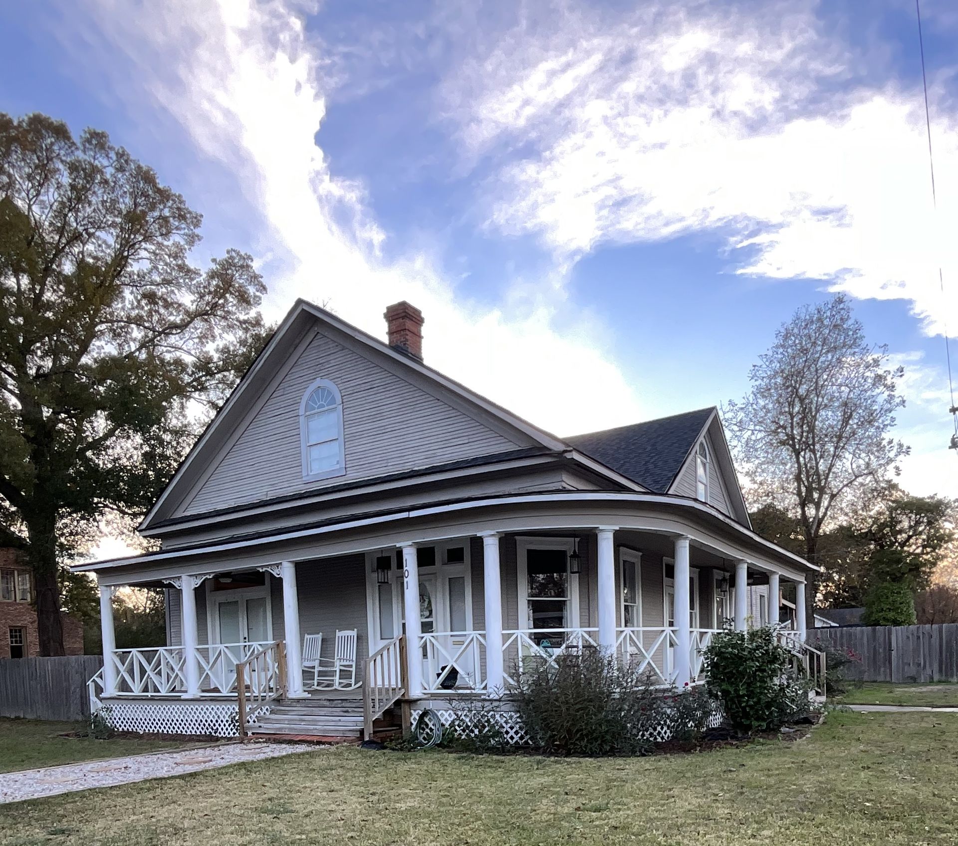 a white house with a large porch and a brick chimney
