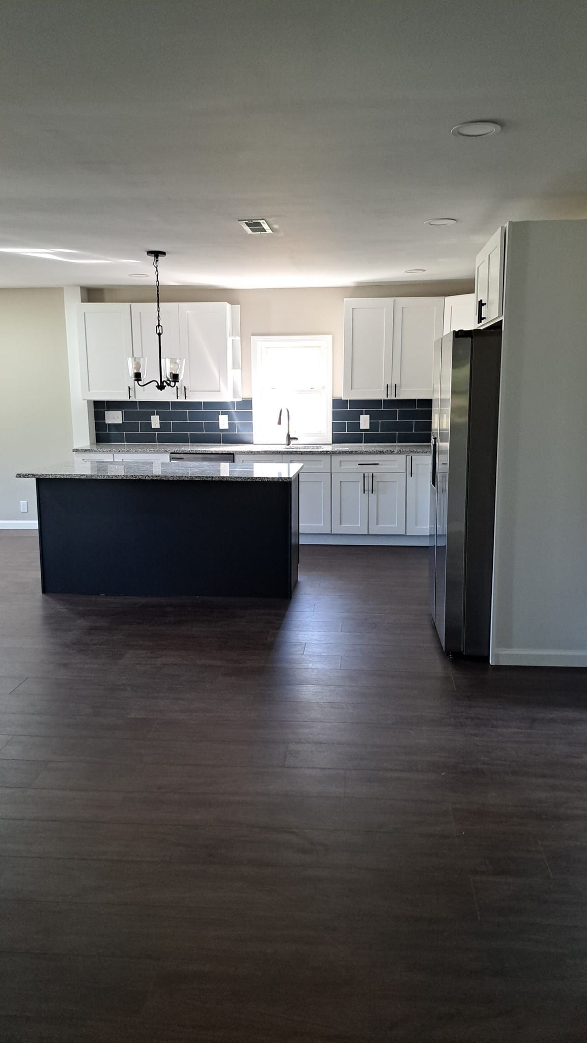 An empty kitchen with white cabinets and a black island