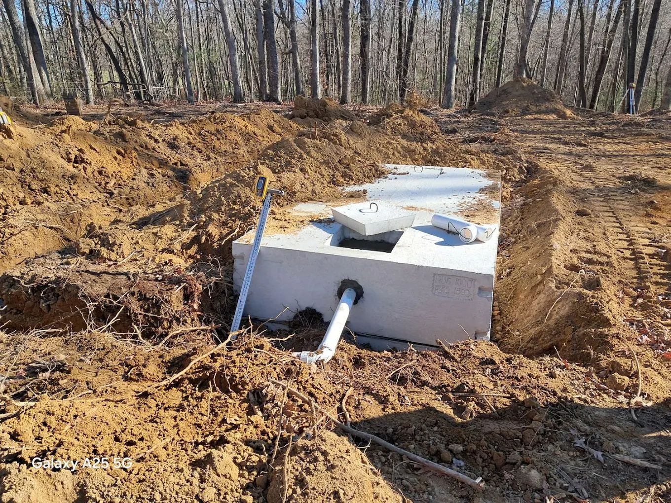 A septic tank is sitting in the middle of a dirt field