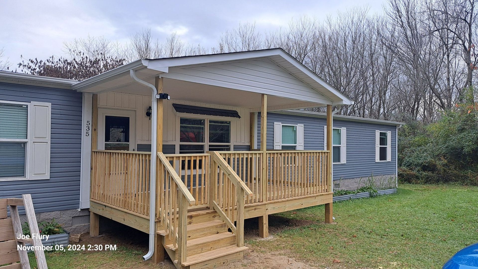 A mobile home with a wooden deck and stairs in front of it