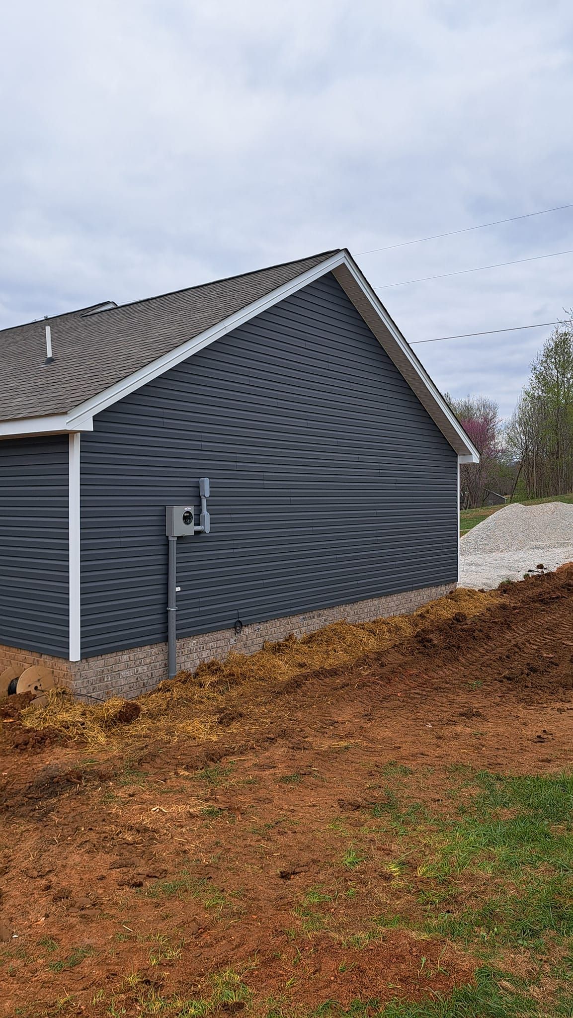 A house is sitting on top of a dirt hill next to a pile of dirt
