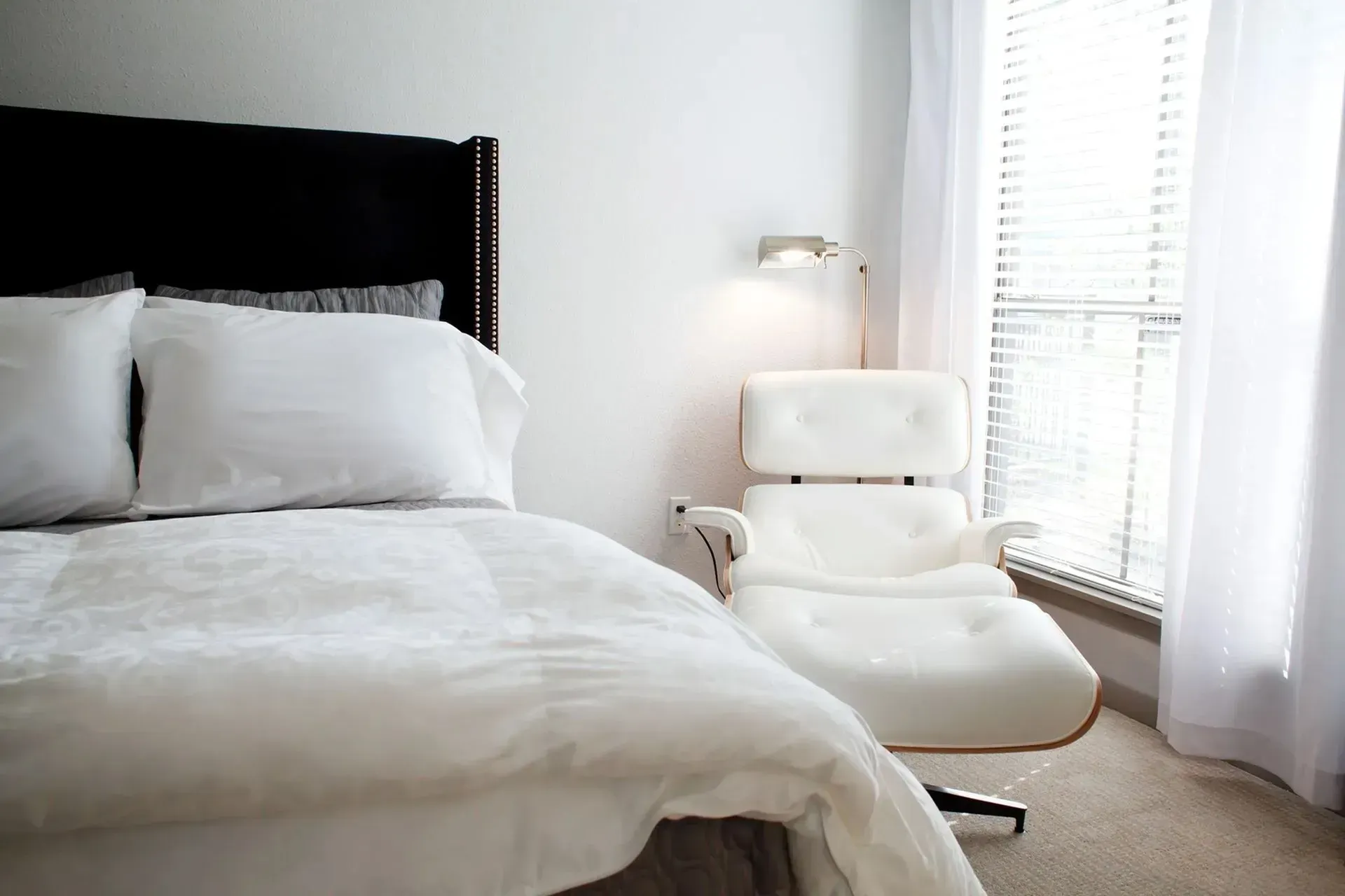 Cozy bedroom with a bed and a white armchair near a window