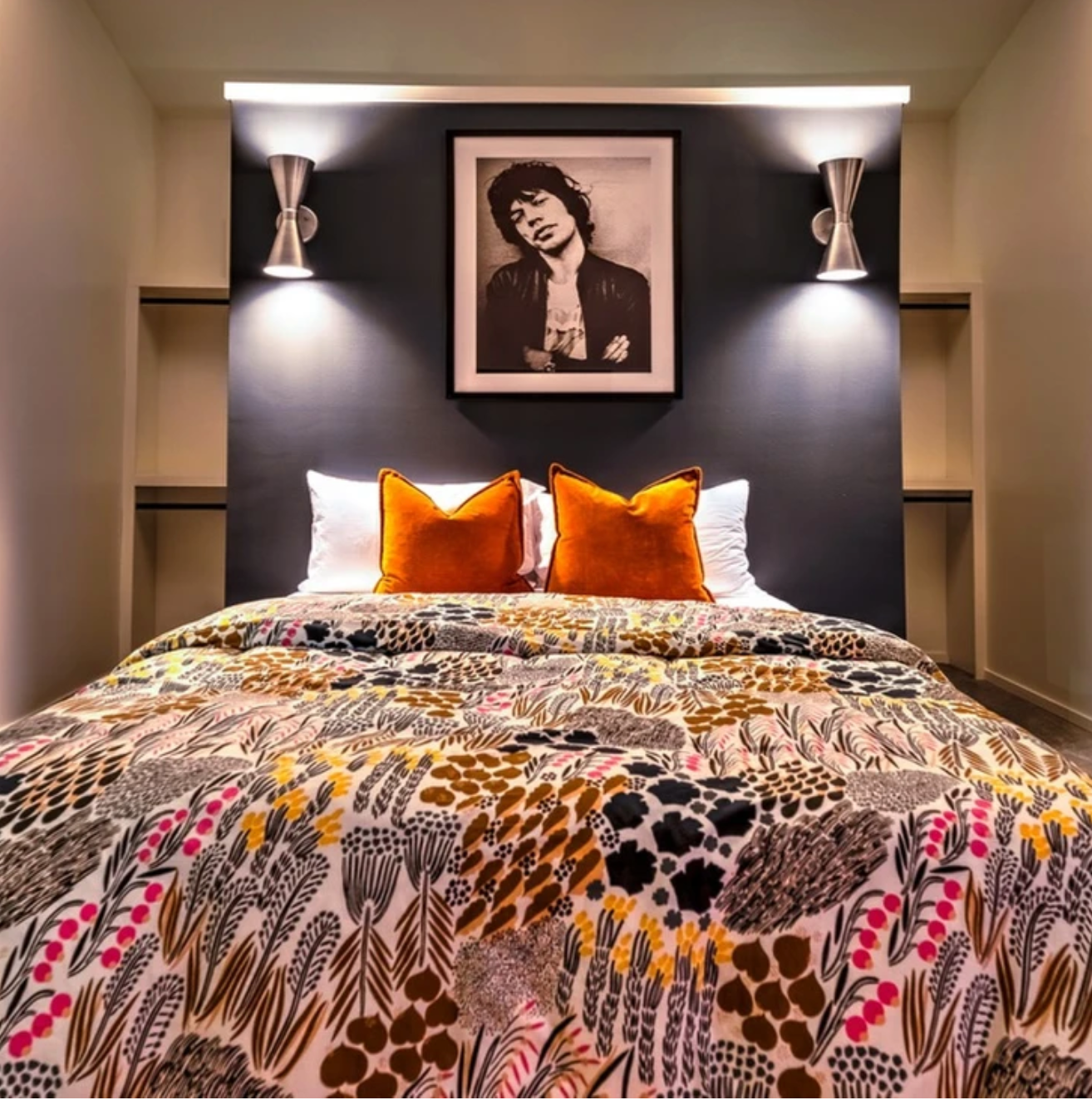 A bed with a picture on the wall above it