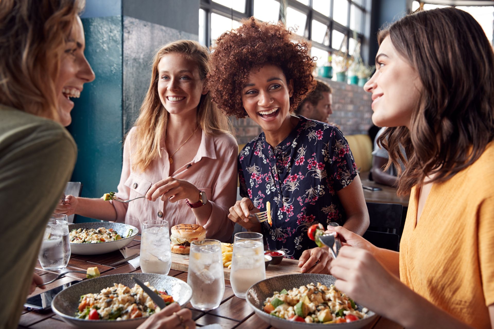 A group of women are sitting at a table in a restaurant eating food.