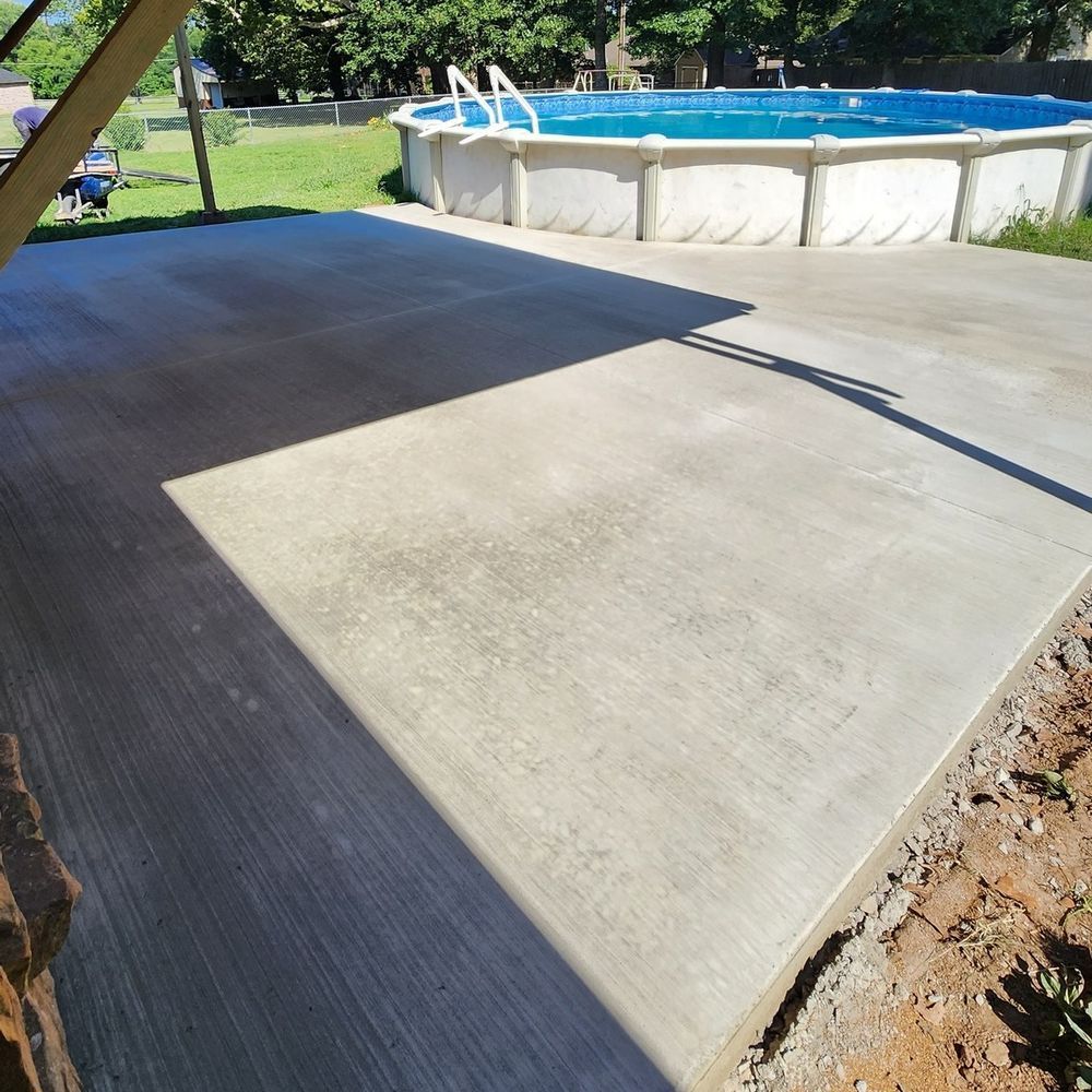 A concrete patio with a pool in the background