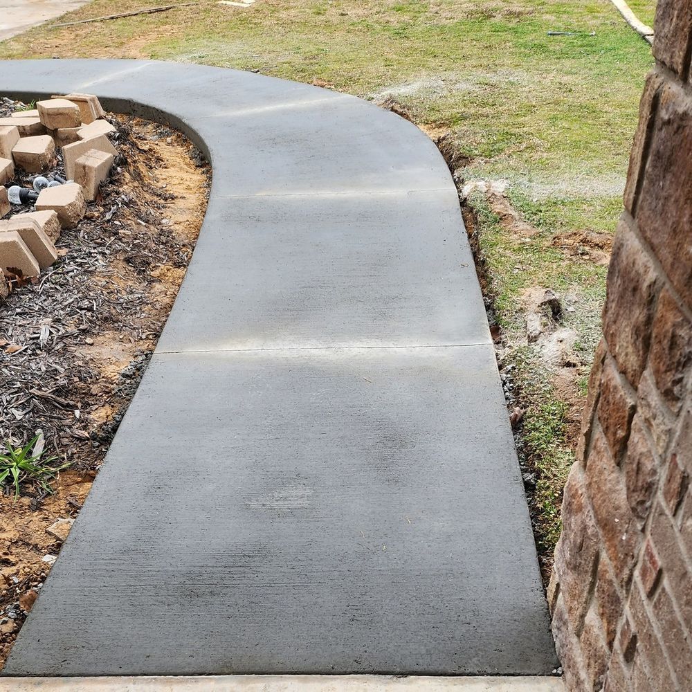 A concrete walkway is being built next to a brick wall