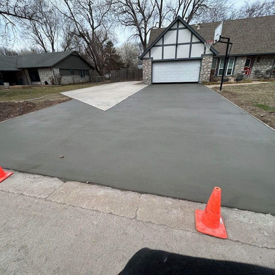 A concrete driveway in front of a house with a basketball hoop