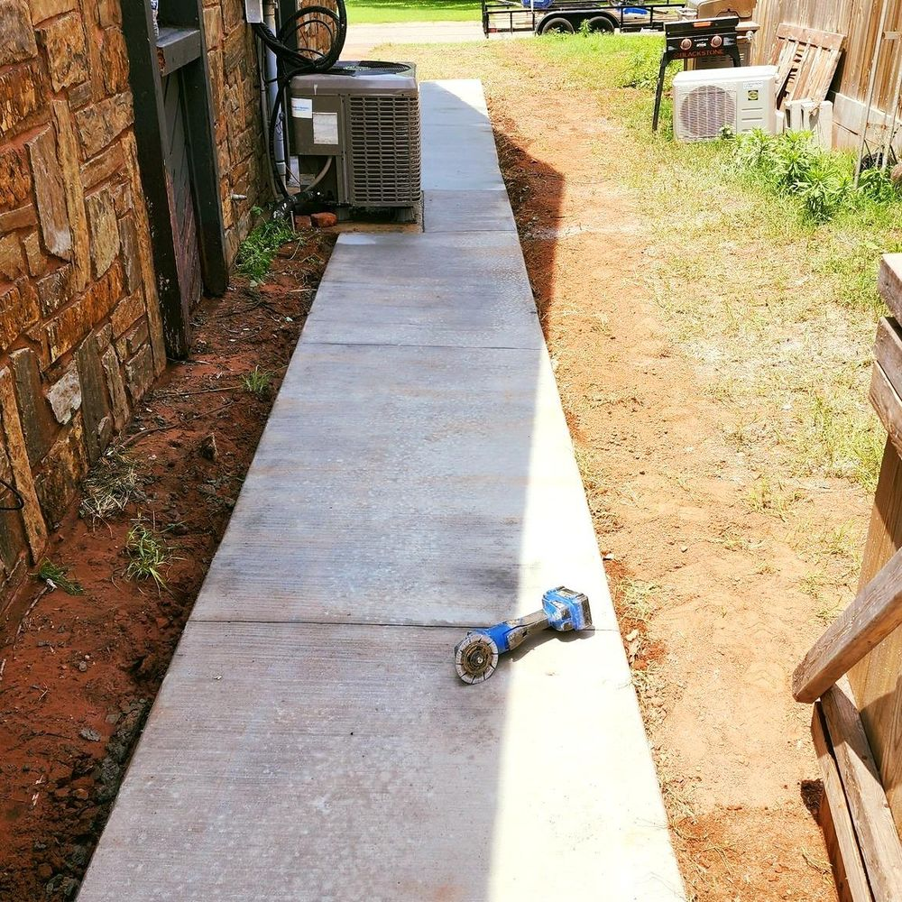 A drill is laying on the sidewalk next to a building.