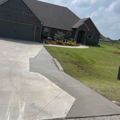 A house with a concrete driveway and a concrete walkway leading to it.