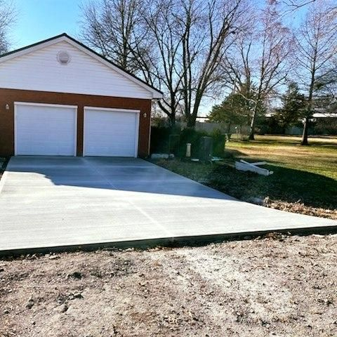 A concrete driveway leading to a garage with two garage doors.
