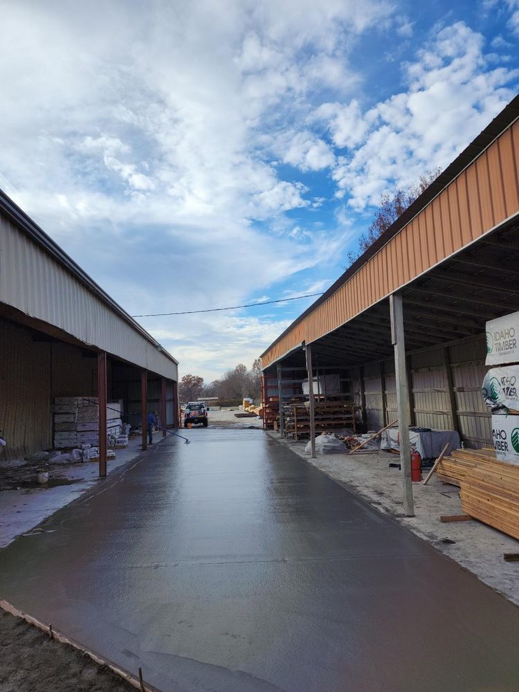 A concrete driveway between two warehouses with a blue sky in the background.